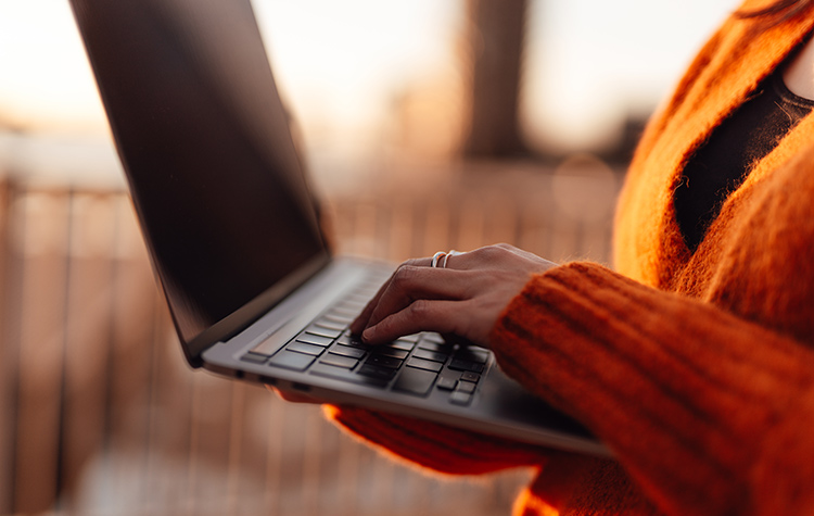 Woman standing with her open laptop in both hands